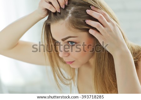 Sad girl looking at her damaged hair