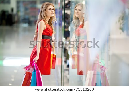 Photo of young joyful woman with shopping bags on the background of shop windows