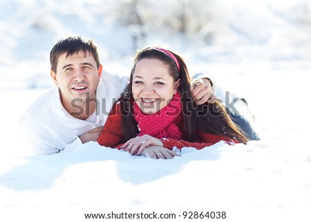Winter couple piggyback in snow smiling happy and excited. Beautiful young couple
