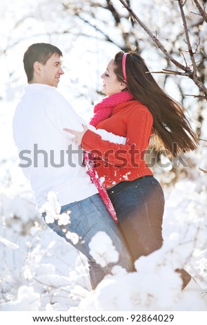 Winter couple piggyback in snow smiling happy and excited. Beautiful young couple