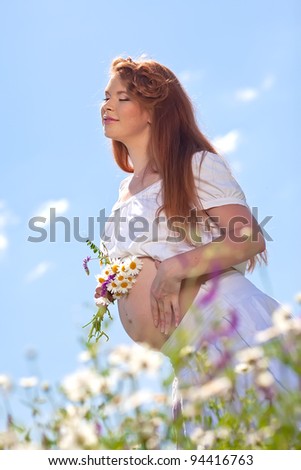 Portrait of pregnant woman on the camomile field