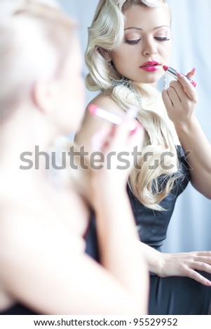 Portrait of beautiful woman applying lipstick
