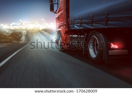 Truck drives on a country road with bokeh lights in the distance