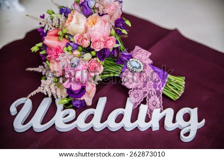 Word of wedding and bridal bouquet on the table, on the burgundy tablecloths