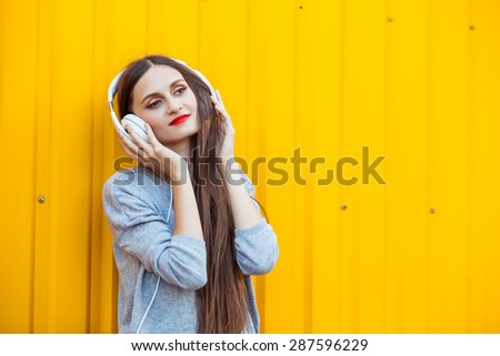 Portrait of Young attractive Teenager in Urban background Listening to Music with White Headphones