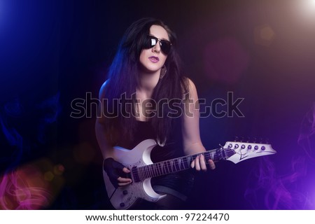 beautiful young rock Guitarist on a dark background