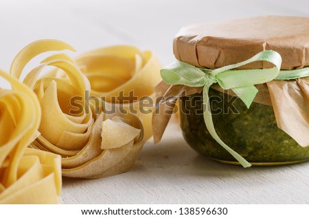 Homemade pesto sauce and raw pasta on white table
