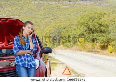 Young woman near broken car speaking by phone needs assistance