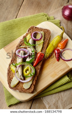 Sprat sandwich with pickled cucumber onion and peppers on the kitchen table