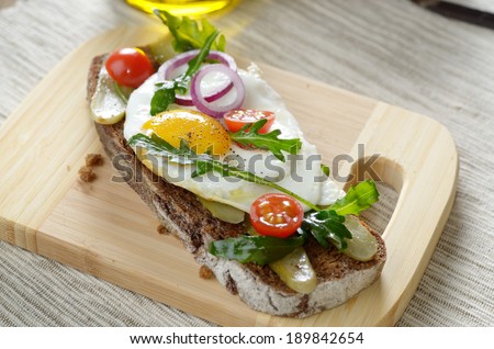 Fried egg and greens open sandwich on the cut board