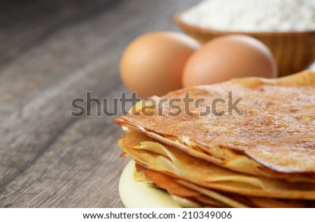 Homemade eggs, pancakes and flour on the wooden table