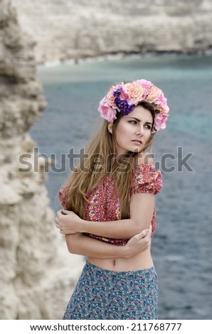 Young beautiful woman in a wreath enjoys sunny day at sea shore