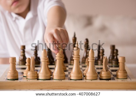 Boy playing chess in the room. Little clever boy concentrated and thinking while playing chess at home.