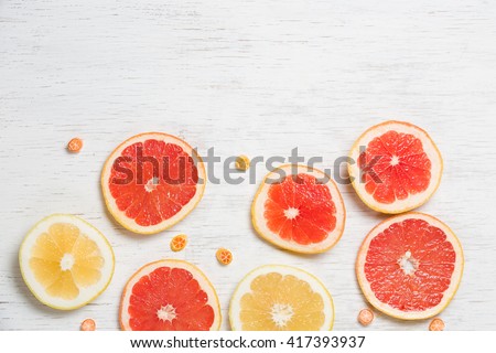 Top view on colorful cut grapefruit on white wooden background. Red and yellow citrus on white board with small candies. Flat lay