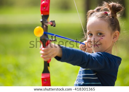 Cute girl archer with bow shooting in sunny summer day. little girl shoots bow in the park. Outdoors. Sport activities with children. Sport and lifestyle concept. Aiming high