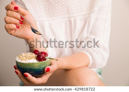 Closeup of woman\'s hands holding a cup with organic yogurt with oats and cherries.  Breakfast or snack. Healthy eating and lifestyle concept.