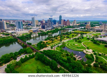 Aerial Over Austin Texas spring time colors with Railroad Tracks crossing Lady bird lake at Zilker Park and Auditorium Shores with Skyline Cityscape and downtown in the background North of the River