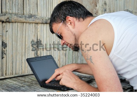 Young man with the computer and its new workplace in jungle