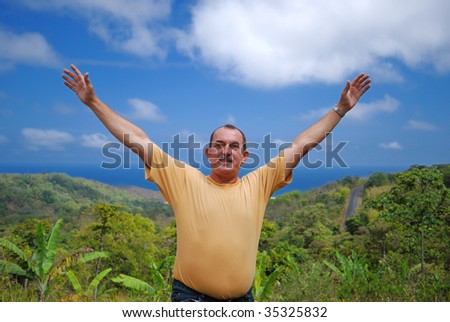 Happy man against the sky, ocean and jungle.
