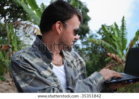 Young man with computer and its new workplace in jungle