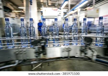 Many bottles on conveyor belt in factory, production of russian traditional alcohol drink vodka