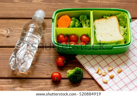 lunch box for kid with fresh vegetables on wooden background