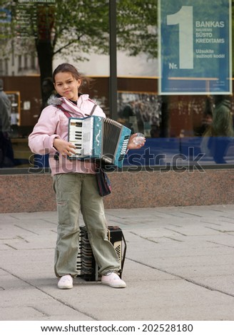 KAUNAS, LITHUANIA - MAY 7: An unidentified gypsy girl with accordion in pedestrian street during Street Music Day on May 7, 2011 in Kaunas, Lithuania