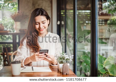 Young Asian beautiful woman using smart phone for business, online shopping, transfer money, financial, internet banking. in coffee shop cafe