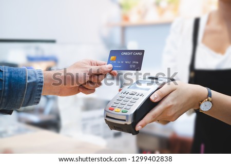 Customer using credit cart for payment to owner at cafe restaurant, cashless technology and credit card payment concept