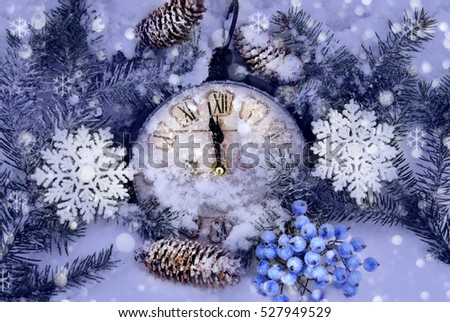 Christmas arrangement in the snow of hours, eating twigs, cones, artificial berries and ornamental snowflakes with the effect of falling snow. Focus on clockwise.