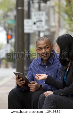 Asian business woman and African business man on their lunch break looking at their Tablet