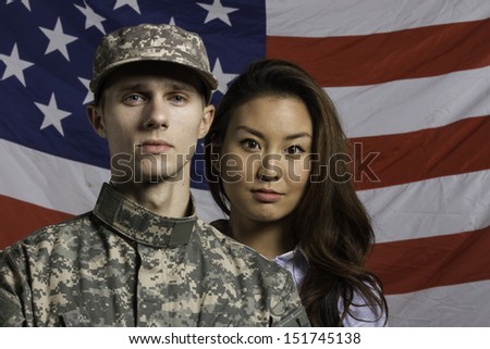 Military man and his wife in front of US flag, horizontal
