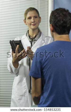Doctor holding tablet and listening to patient, veritcal