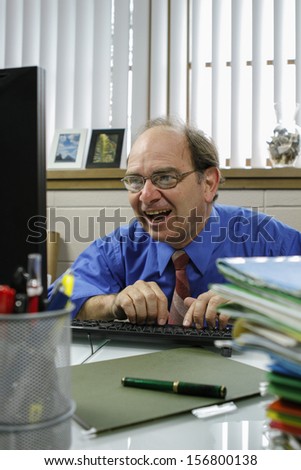 Businessman or boss laughing while working on his computer, vertical