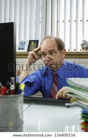 Frustrated businessman at his computer in his office, vertical