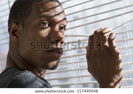 Young black man looking out window, horizontal