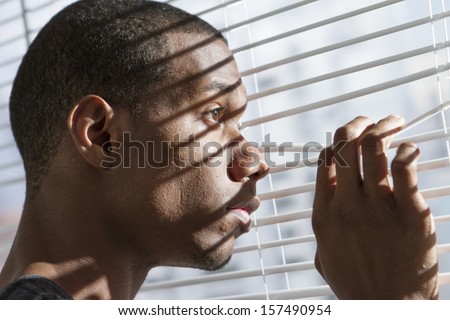 Young black man looking out window, horizontal
