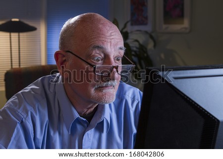 Man looks surprised at content on computer monitor, horizontal