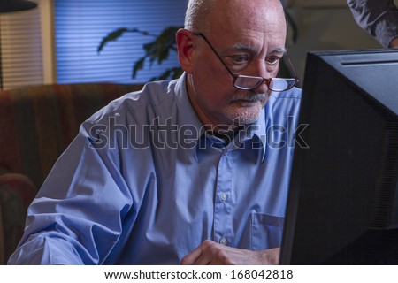 Older man using his computer at night, horizontal