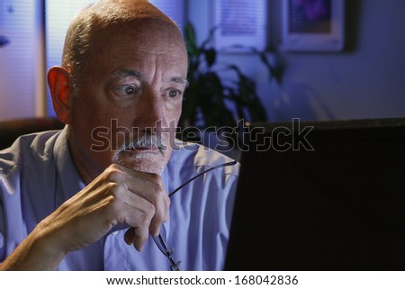 Older man studying computer, horizontal