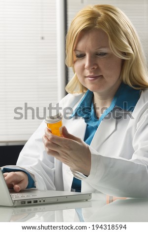 Female Doctor checking prescription drug at computer.