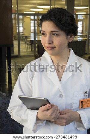 Hispanic female in labcoat, holding tablet, profile shot