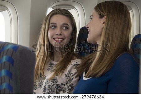 Mother and daughter talking with each other on an airplane