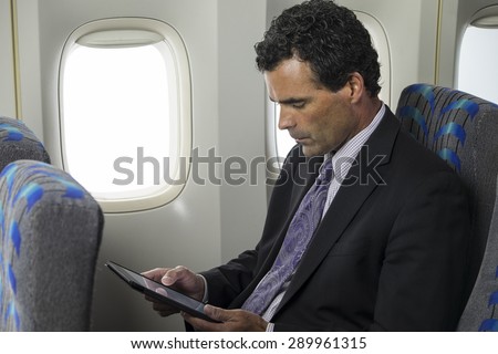 Business man on a plane using an ipad/tablet