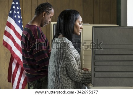 Young black woman and older black male voting in a booth