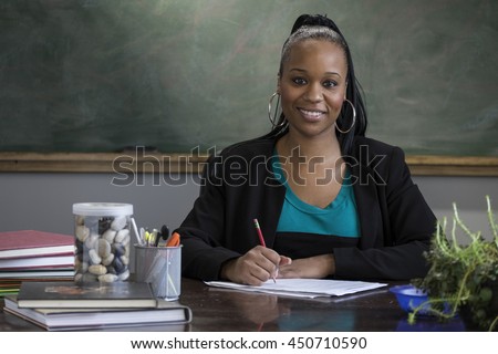 Black female teacher grading school papers