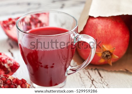 Glass of pomegranate juice with fresh fruits on white rustic wooden table