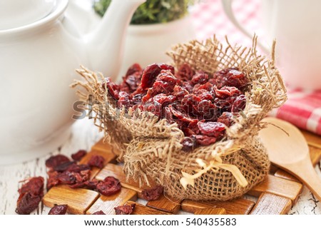 Dried cranberries in burlap bag on white rustic table