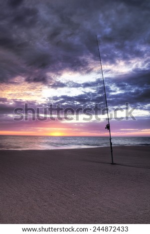 Atlantic Ocean beach with fishing rod planted in the sand