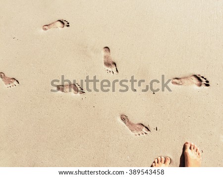 Feet and steps marks on sunny sand beach by sea, summer travel photo,  close up footprints in sand, yellow sand with step marks, vacation by sea, summer holiday, girl on holiday, Bali, Indonesia